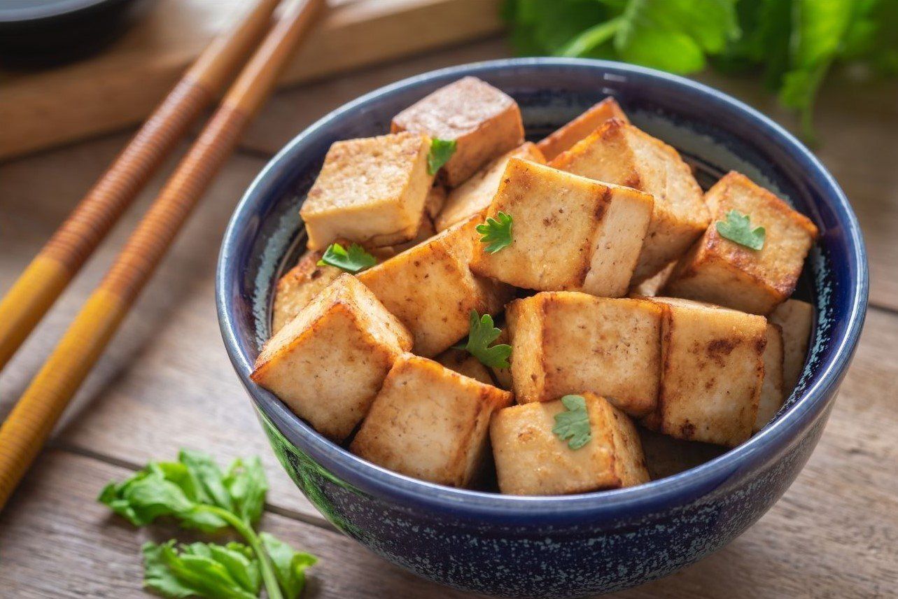 Cubed and seasoned tofu in a bowl with chopsticks