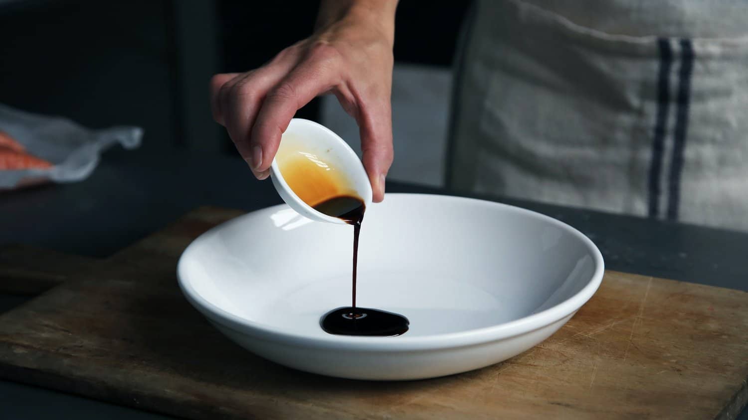 Soy sauce being poured into a white bowl