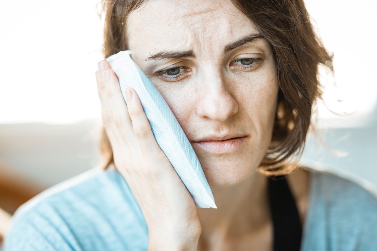 Woman with a toothache holding an ice pack to her jaw