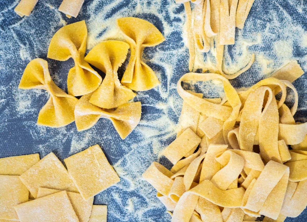 Fresh bowtie pasta and fettuccine on a blue countertop